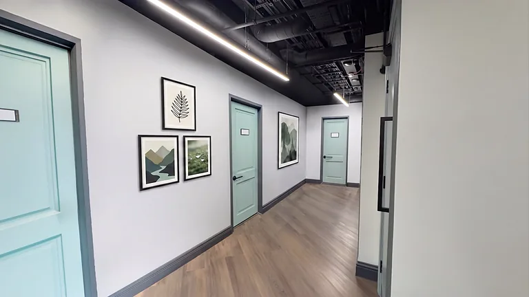 Bright corridor with pale blue doors, framed leaf prints and a wood floor