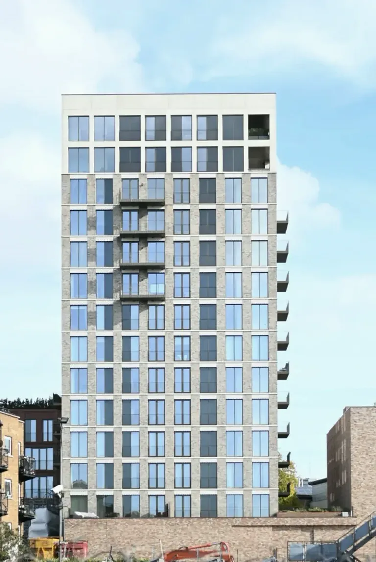 Tall residential tower with balconies against a blue sky