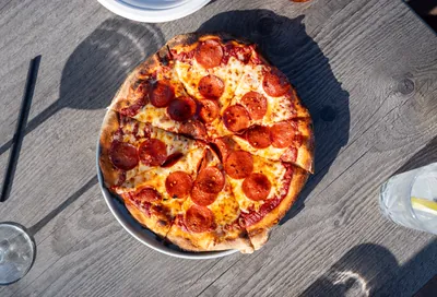 Pepperoni pizza on a sunlit table at Apex Lounge